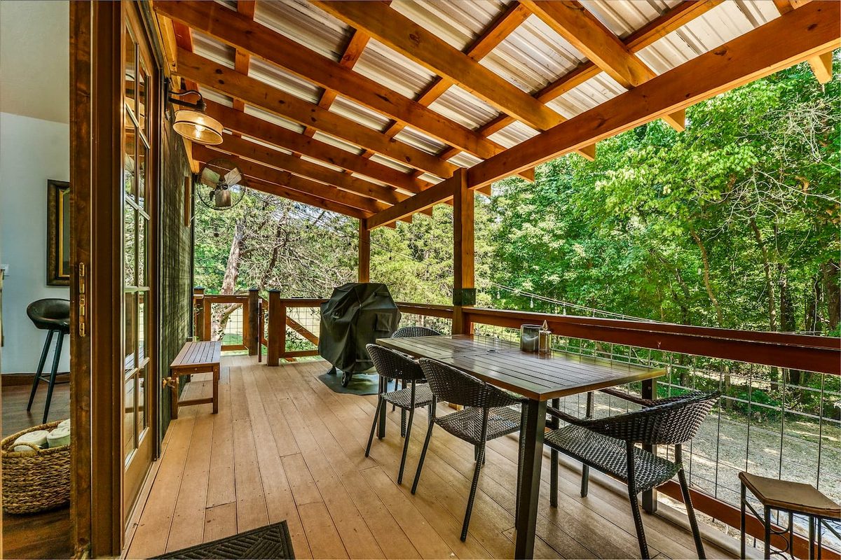 Cedar pergola porch with an outdoor dining table and woodland views