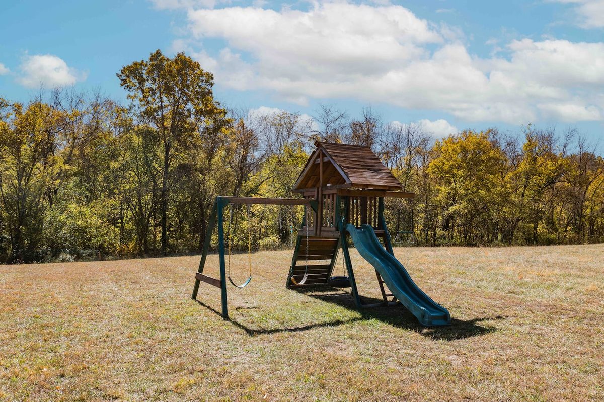 Outdoor playground with a slide, swings and climbing fort on the cabin lawn