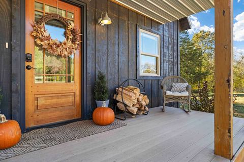 Front porch with stacked firewood, pumpkins and a seasonal wreath