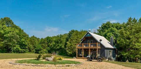 The cabin on a clear day with the UTV parked beside the gravel drive