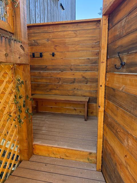 Inside the private cedar outdoor shower enclosure with a teak bench
