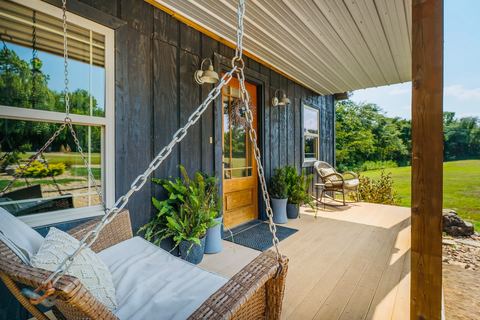 Porch swing suspended by chains against the cabin’s dark board-and-batten siding
