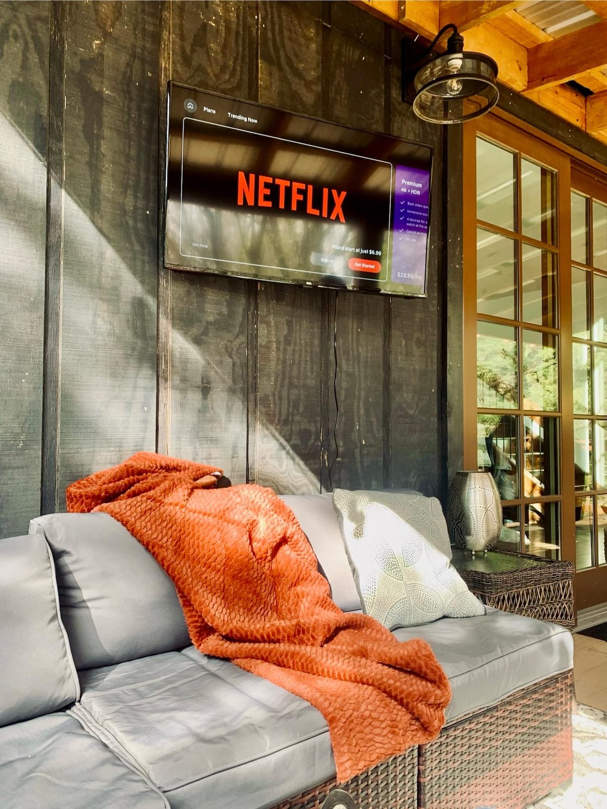 Covered back porch with an outdoor TV and sectional sofa — perfect for a rainy day at the cabin