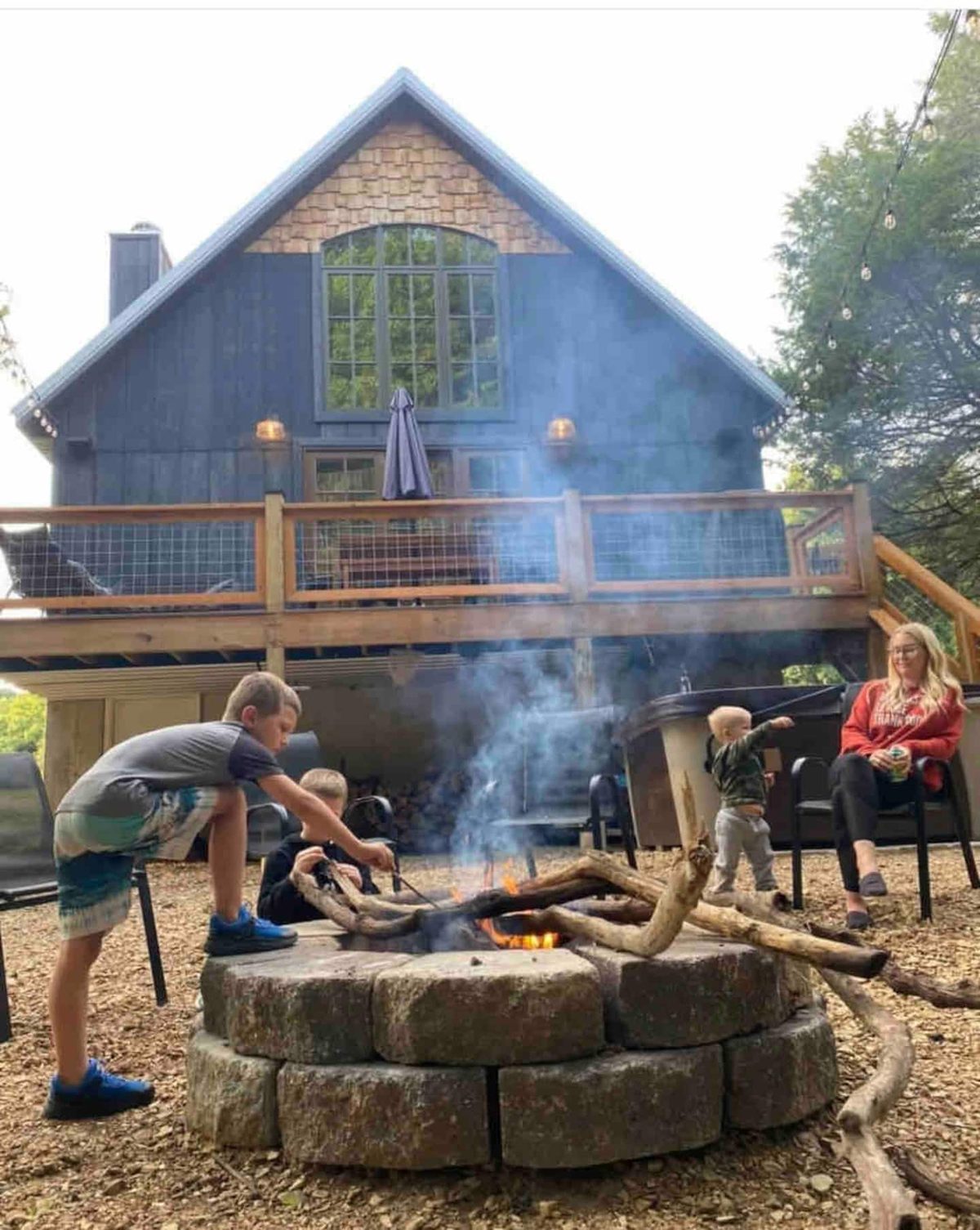 Guests gathered around the stone fire pit with the cabin lit up behind them