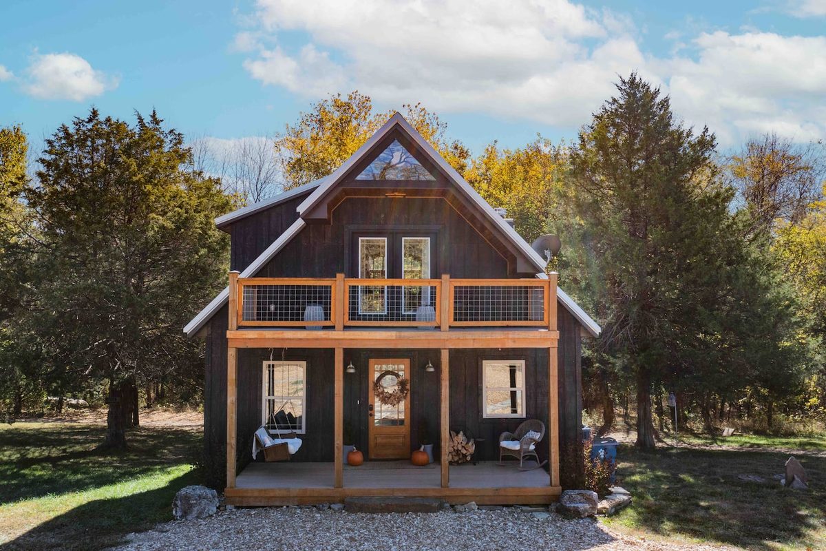 Front of the James River Cabin in autumn, board-and-batten siding with a covered porch and balcony above